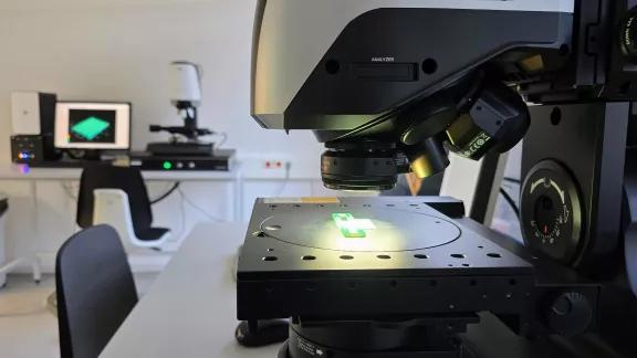 A digital microscope with polarized light analyzer positioned over a small green component for micro-scale inspection