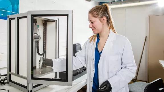 A lab technician positions a sample cylinder inside the GranuPack automated tap density instrument