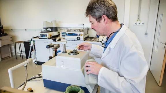A lab technician loads mounting compound into a metallographic sample preparation press