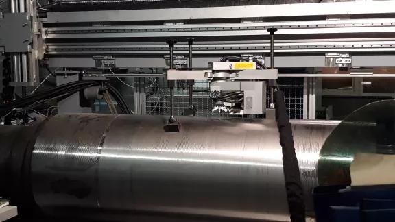 An X-ray diffraction residual stress measurement head positioned on a large steel cylindrical component in the lab