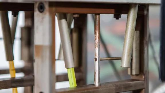 Close-up of weighted loading rods positioned above a sample in an HDT and Vicat testing apparatus