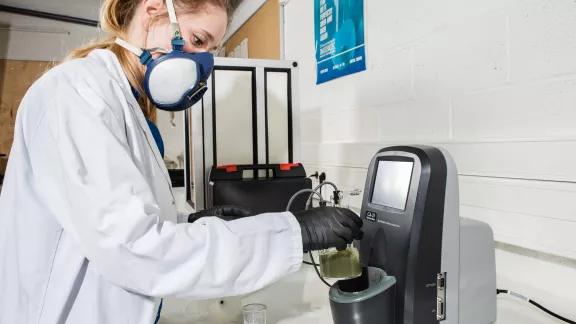 Laboratory technician placing a sample vessel in a coulometric moisture meter