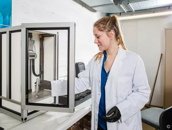 A lab technician positions a sample cylinder inside the GranuPack automated tap density instrument