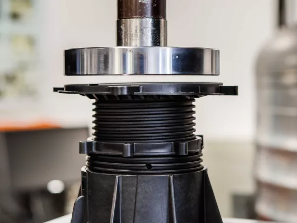 A test sample is positioned under the compression plate of a testing machine, ready for loading