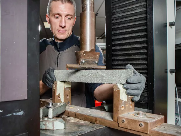 A lab technician positions a composite sample in a three-point bending fixture on an Instron testing machine