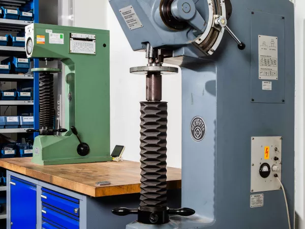 Two hardness testing machines, including a large Reicherter Brinell tester, set up on a lab workbench