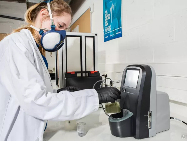 Laboratory technician placing a sample vessel in a coulometric moisture meter