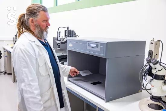 A lab technician places a metal test panel into a Verivide light box used for color measurement