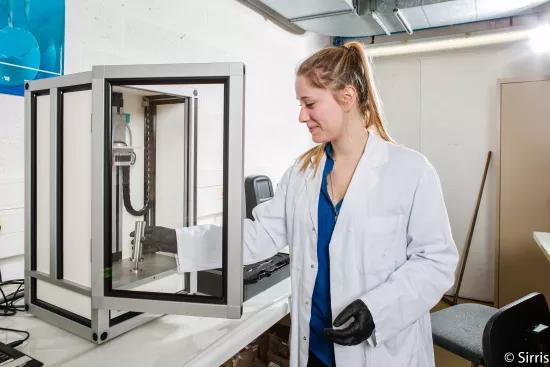 A lab technician positions a sample cylinder inside the GranuPack automated tap density instrument