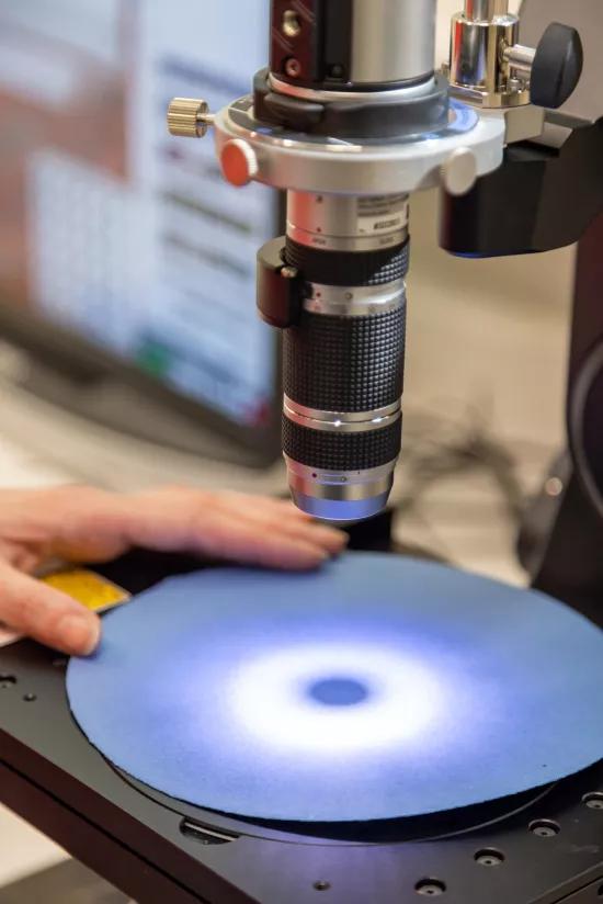 Sample disc positioned under a digital microscope objective for material analysis