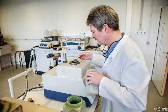 A lab technician loads mounting compound into a metallographic sample preparation press