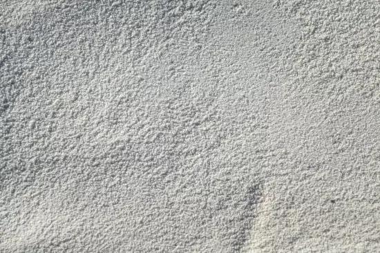 Close-up of a fine white granular powder, representative of samples used in gas pycnometry density testing