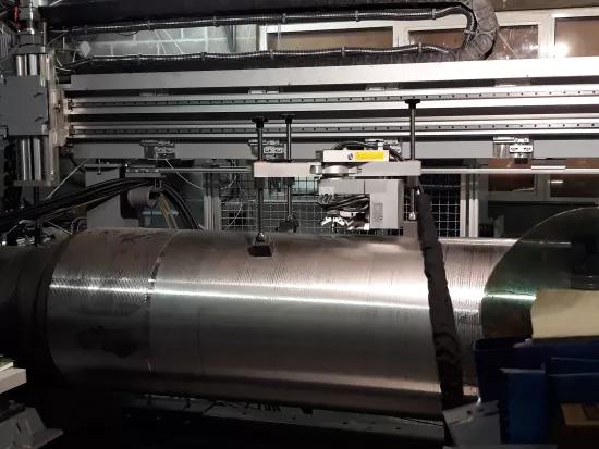An X-ray diffraction residual stress measurement head positioned on a large steel cylindrical component in the lab